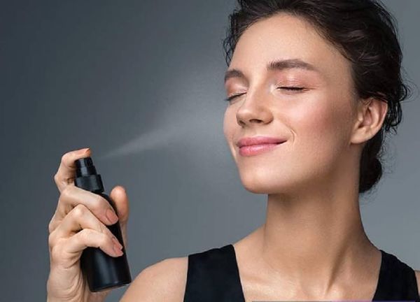 una donna vaporizza lo spray fissante sul viso per allungare la durata del make-up